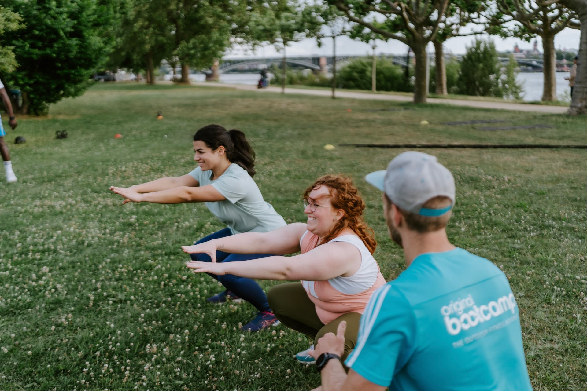 Bootcamp Teilnehmerinnen werden bei Kniebeugen vom Personal Trainer betreut